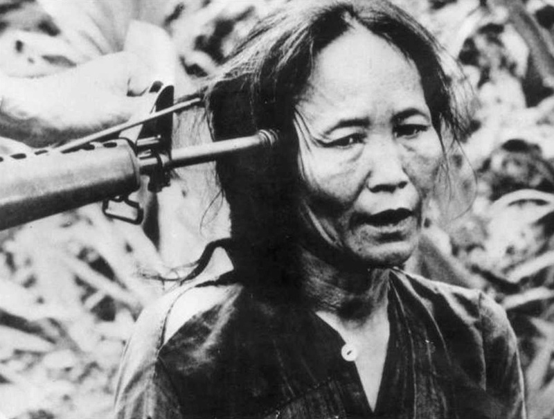 Вьетнамская женщина с оружием, приставленным к ее голове. Вьетнамская война. 1969. Черно-белая фотография. <br> © Keystone / Hulton Archive / Getty Images
